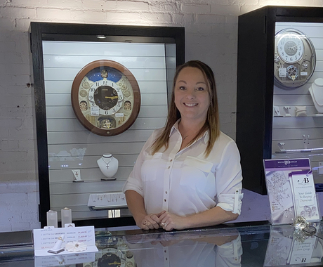 Woman standing behind jewelry counter, posing