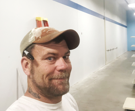 Man in construction clothes with new wall behind him