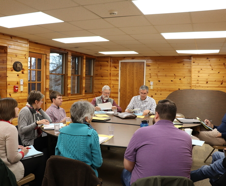 people sitting around table, talking and taking notes