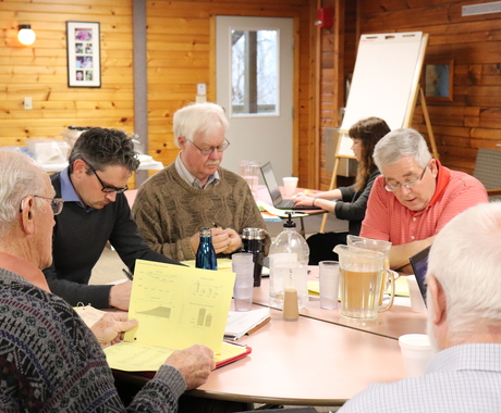 men sitting around a table talking and looking at documents