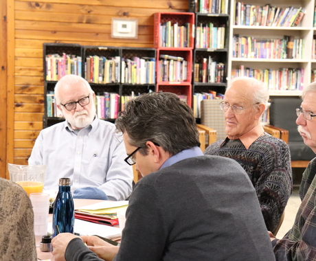 men gathered around table discussing