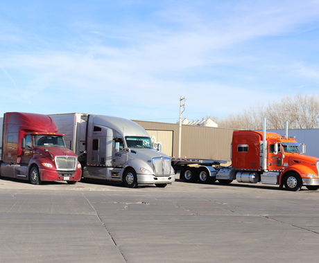 three semi trucks parked at a truck stop