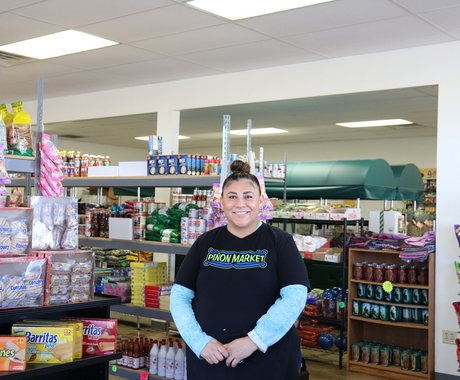 Woman stands in grocery store with racks of goods behind her