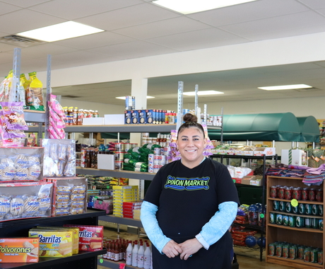 Woman stands in grocery store with racks of goods behind her