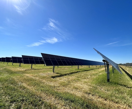 solar arrays with grass underneath and blue sky above
