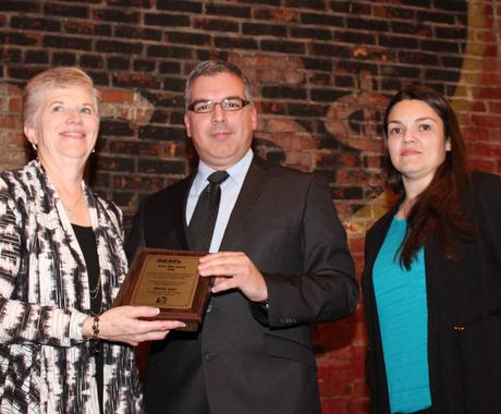 Two women and man with award