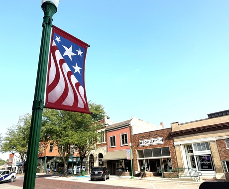 American flag design banner on light pole with buildings in the background