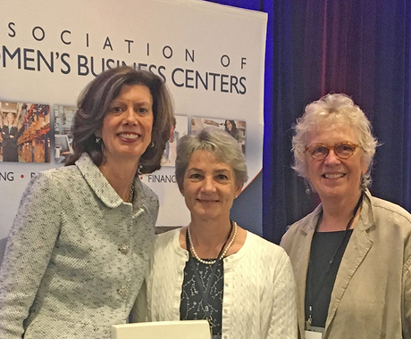 Three women standing on stage at conference