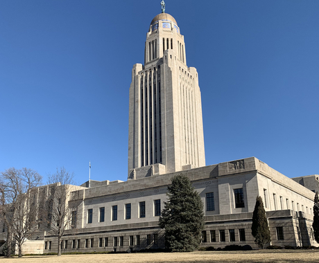 Nebraska State Capitol building - a flat 2-story granite building with a spire raising out of the middle, with a bronze dome on top
