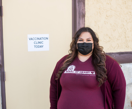 Woman standing in front of door with "Vaccination Clinic Today" sign
