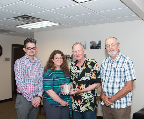 Three men and one woman with award