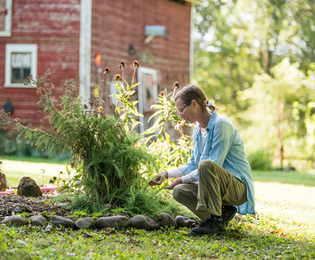 Woman business owner with herbs in front of barn