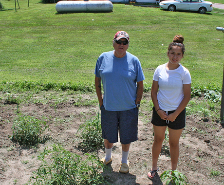 Man and granddaughter standing in garden