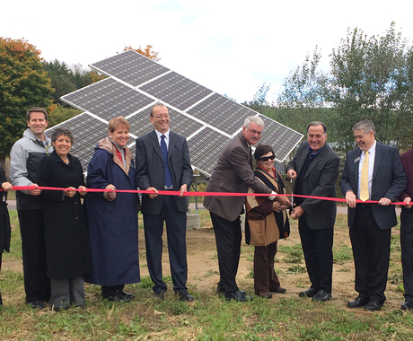 Group of people at a ribbon cutting in front of solar array