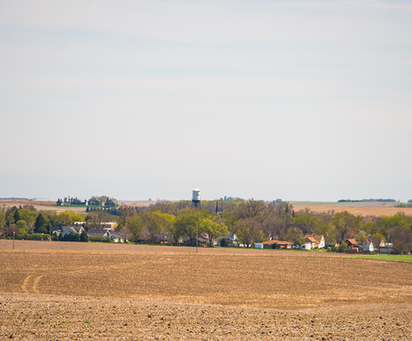 harvested field with town skyline in background