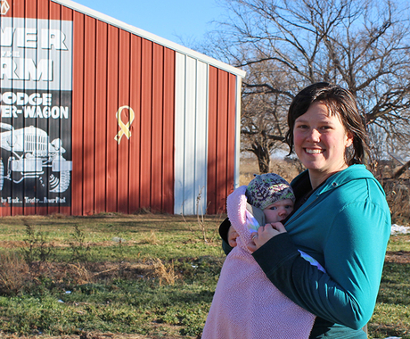 Woman with baby in front of shed and fruit trees