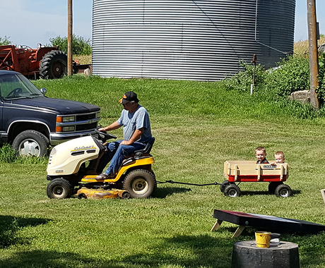 Man on lawnmower pulling children in wagon