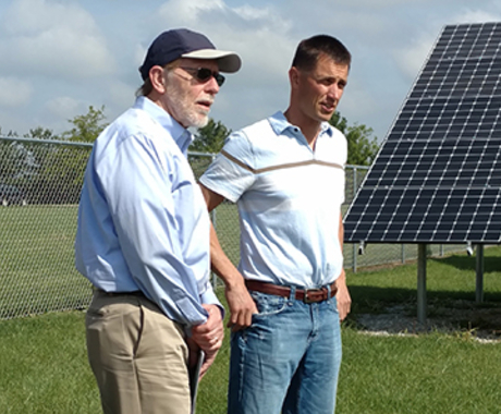 Three men in front of solar panel