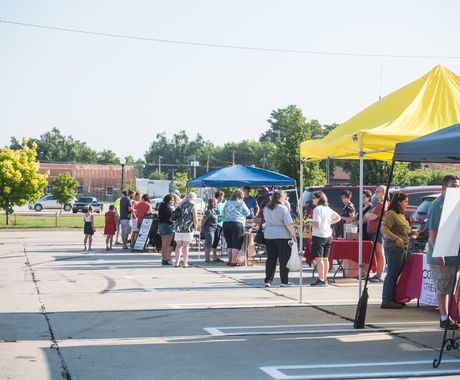 A row of farmers markets booths with blue and yellow tents.