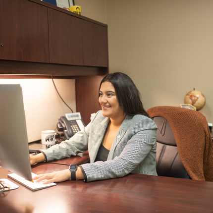 Mujer latina sentada en un escritorio frente a un IMac