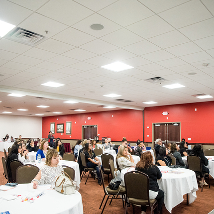 People sitting at tables, listening to speaker