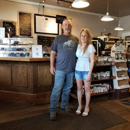 man and woman standing and smiling in front of counter in coffee shop
