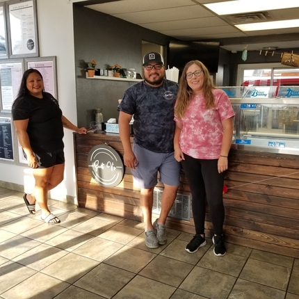 2 women and man standing in front of counter, posing
