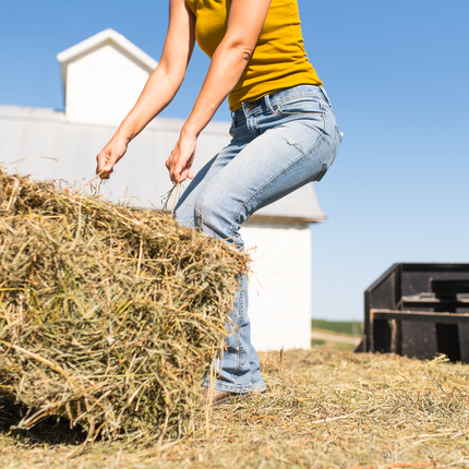 Female farmer lifting hay bale