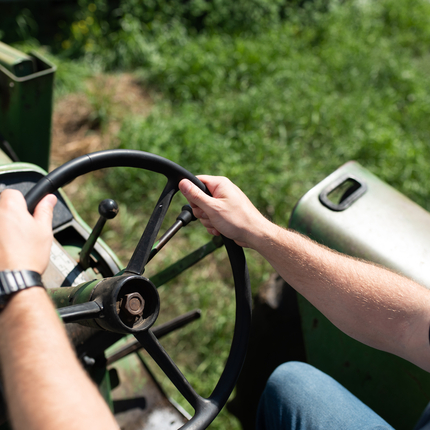 Hands on a tractor wheel, view is over the shoulder looking down