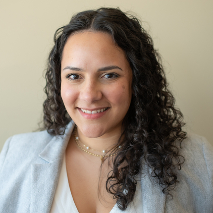 Woman with curly brown hair and gray jacket