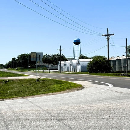 A road going by a town with a water tower and buildings in the background.