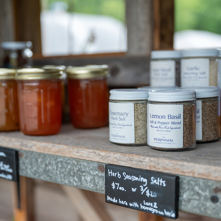 A shelf with glass jars of jam and glass jars of a spice blend