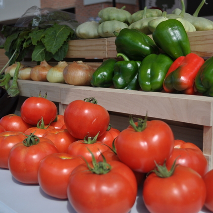 Tomates, cebollas, pimientos y otras verduras en un stand.