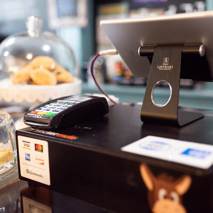Caja registradora con maquina de tarjetas de crédito o debito al lado y recipientes con pastelitos a la izquierda