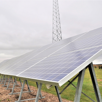 Solar array sitting on a green grass field.
