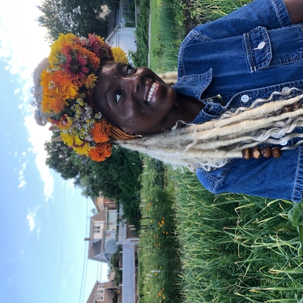Tricey Chea posing for a photo in a field of greens with a flower head piece