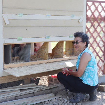 Patricia Pinto kneels by chicken coop