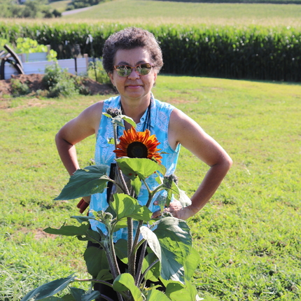 Patricia Pinto se para en el patio con un campo de maíz al fondo