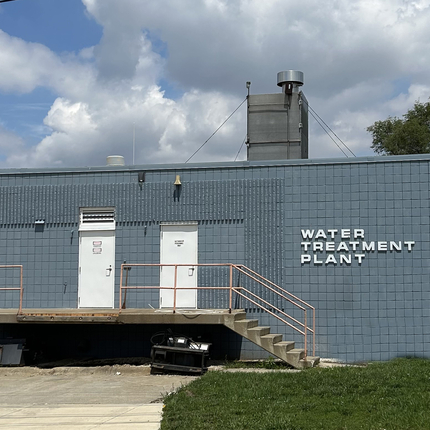 A one-story blue bricked building with two white doors. White lettering on the building says "Water Treatment Plant"