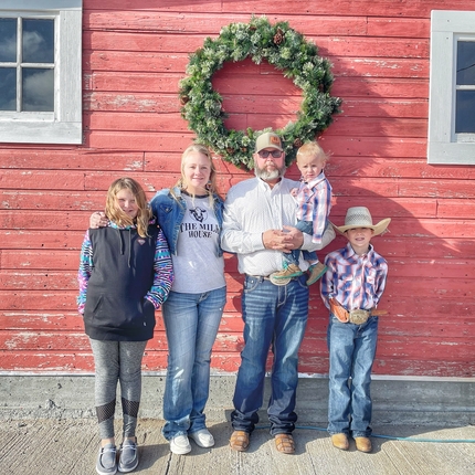 Family standing against barn with wreath in background