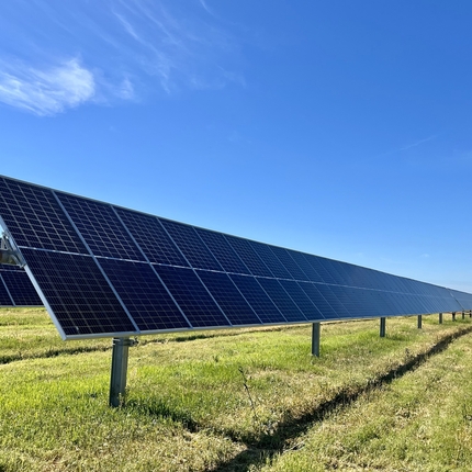 Paneles solares sentados en un campo bajo un cielo azul.