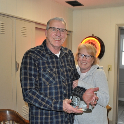 A man and a woman holding an award in front of lockers.