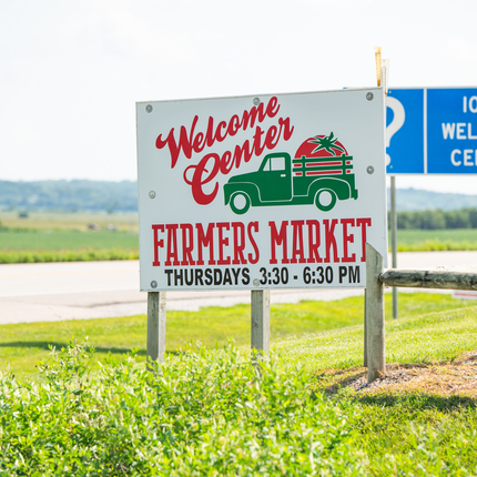 Cartel cerca de una carretera que dice "Welcome Center Farmers Market"