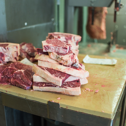 A pile of cut beef steaks on a butcher table