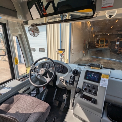 Vista de un autobús escolar, justo detrás del asiento del conductor. Incluye el volante y el panel de control.
