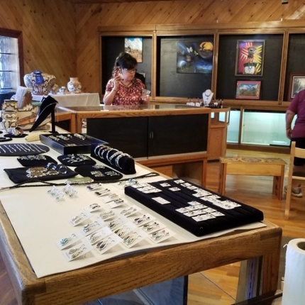 Woman in far back looks at jewerly in three long glass and wood jewerly displays