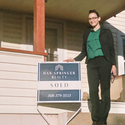 Alexandra Henry standing in front of a "sold" home sign