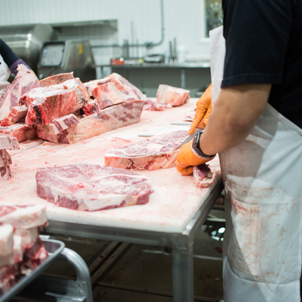 Workers cutting meat at a processing facility 