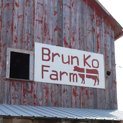 Casa de campo con un letrero que dice Brunk Ko Farm y un diseño de vaca en rojo.