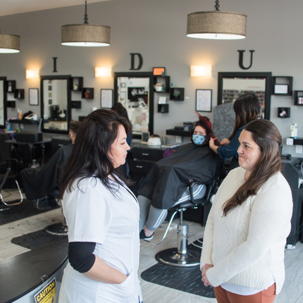Two women standing in a hair salon facing one another